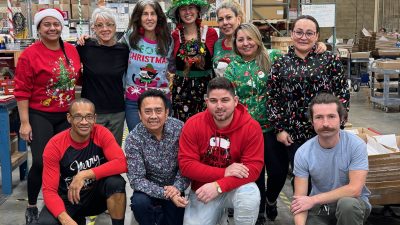 a group of people wearing colorful sweaters for ugly sweater day in the plant