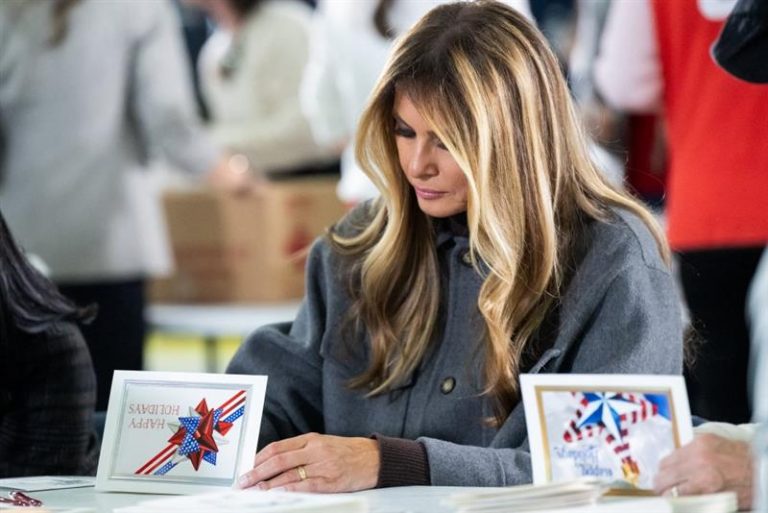 The First Lady signs a patriotic holiday greeting card during a Red Cross care-package event for service members.